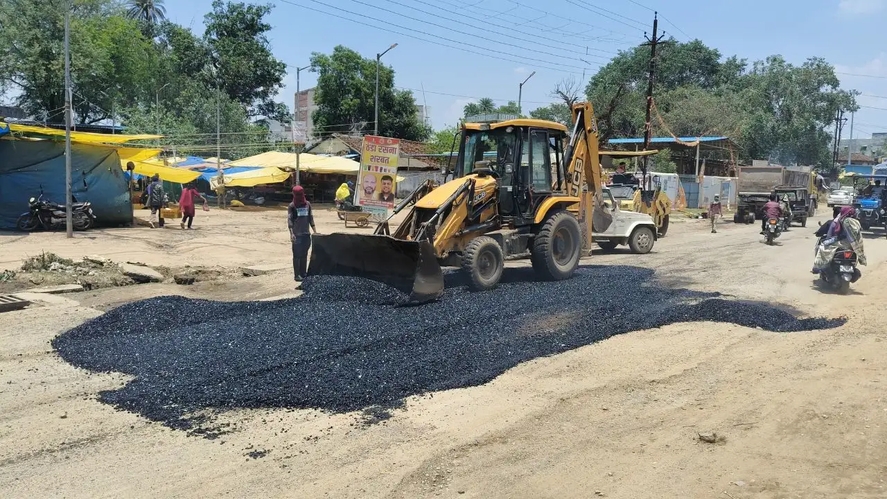 Asphalt is being laid using a JCB.
